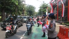 Aksi Simpatik :Banyak pengendara yang secara sukarela menghentikan kendaraan untuk menerima bendera dari anggota Brimob yang membagikannya dengan ramah dan penuh semangat. (HUMAS PMJ)