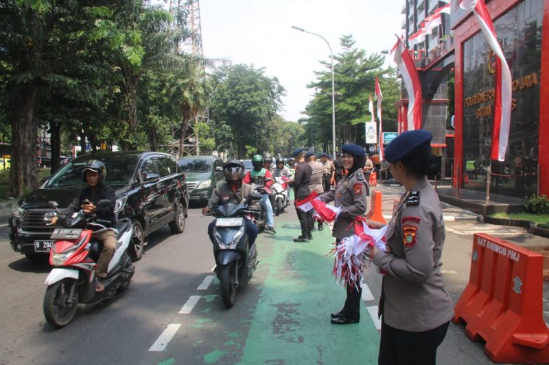 Aksi Simpatik :Banyak pengendara yang secara sukarela menghentikan kendaraan untuk menerima bendera dari anggota Brimob yang membagikannya dengan ramah dan penuh semangat. (HUMAS PMJ)